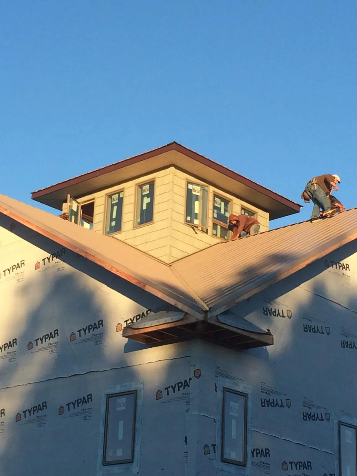 Roofers working around a rooftop cupola on a new metal roof at sunset — Roof Waterproofing in Rome by Roofing Brothers